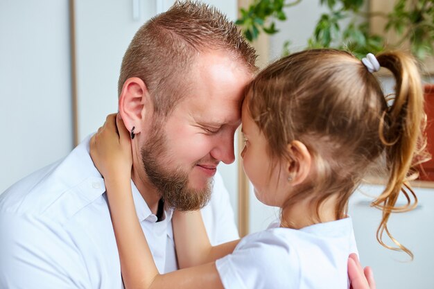 Adorable niña de vestido blanco abrazando amoroso padre