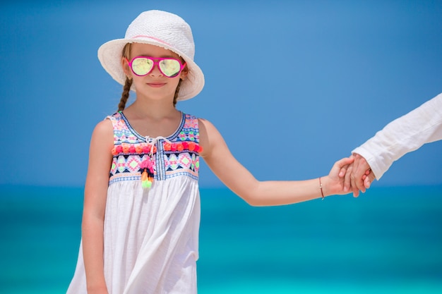 Adorable niña con vestido blanco en la playa durante las vacaciones de verano