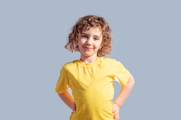 Adorable niño de 5 años en camiseta amarilla posando en gris