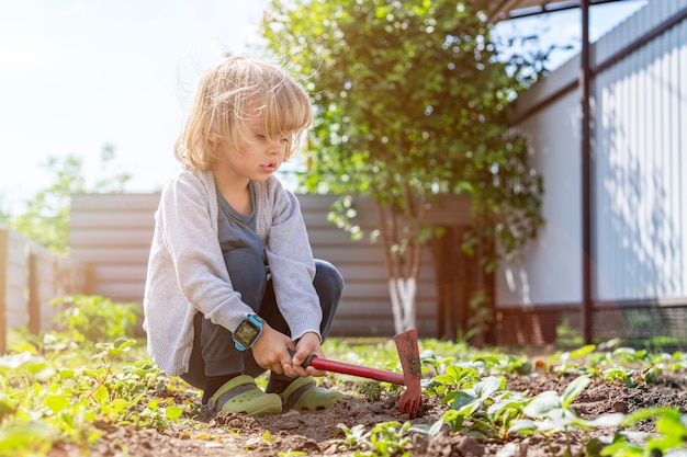 Adorable niño ayudando a los padres a cultivar verduras y divertirse.