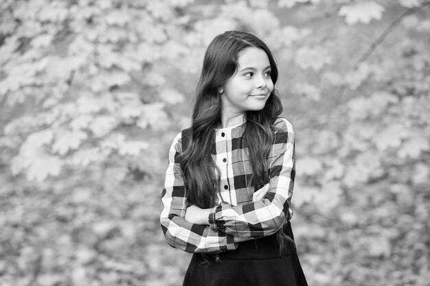 Adorable niño con cabello largo disfruta de la temporada de naturaleza otoñal