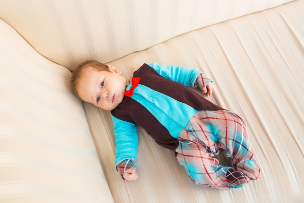 Adorable niño con cabello rojo y ojos azules. Lyling niño recién nacido en el sofá.