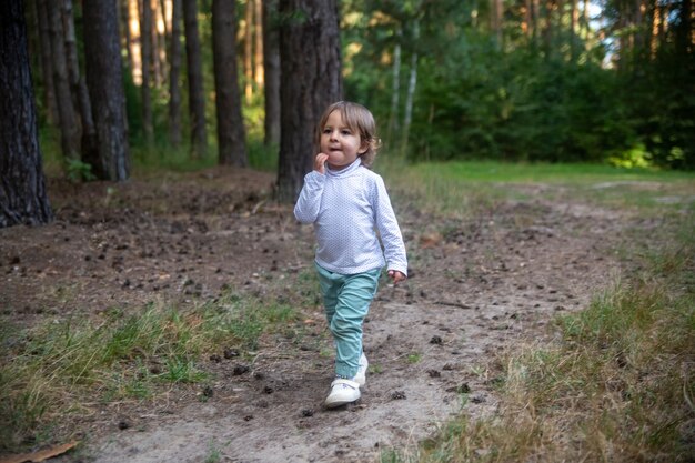 Adorable niño camina en el bosque bosque día soleado de verano