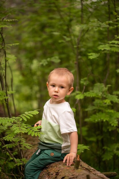 Adorable niño caucásico en el bosque contra el fondo de la hierba en verano