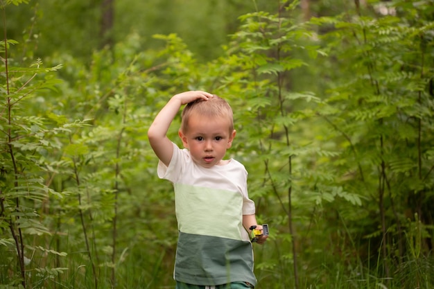 Adorable niño caucásico en el bosque contra el fondo de la hierba