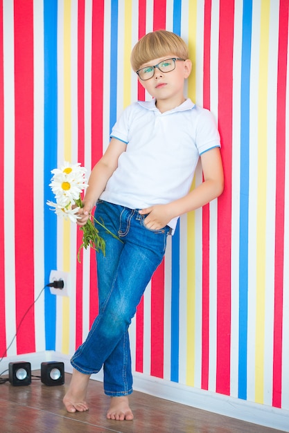 Adorable niño en colores de fondo. Niño lindo en el interior en estudio cerca de la pared.