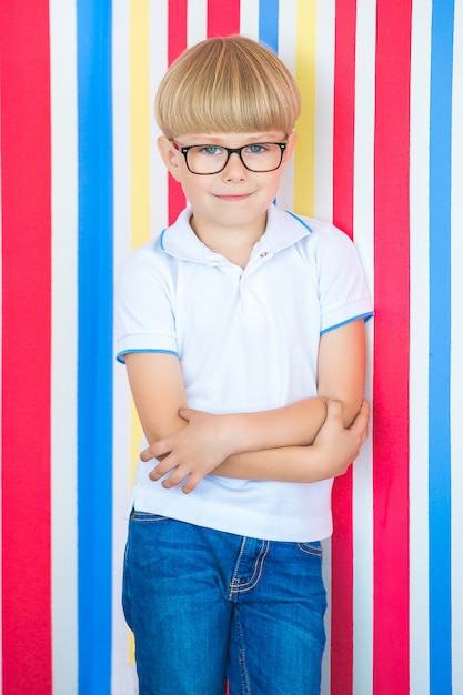 Adorable niño en colores de fondo. Niño lindo en el interior en estudio cerca de la pared.