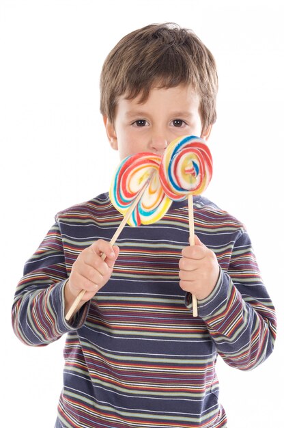 Foto adorable niño comiendo dos piruletas sobre fondo blanco