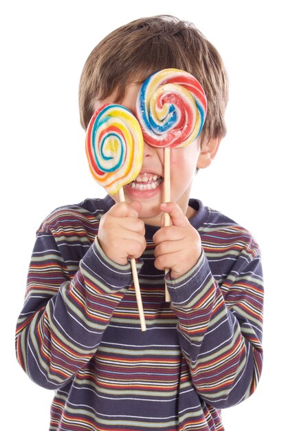 Foto adorable niño comiendo dos piruletas sobre fondo blanco