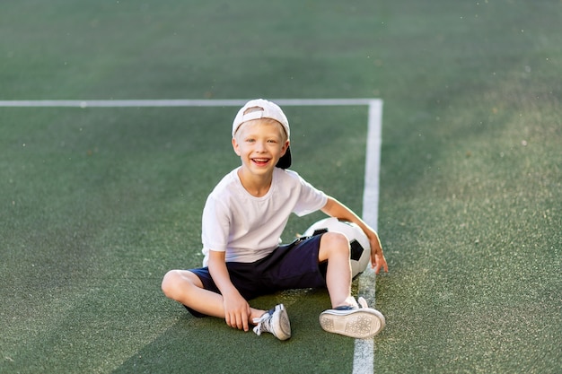 Adorable niño deportivo en el campo de fútbol