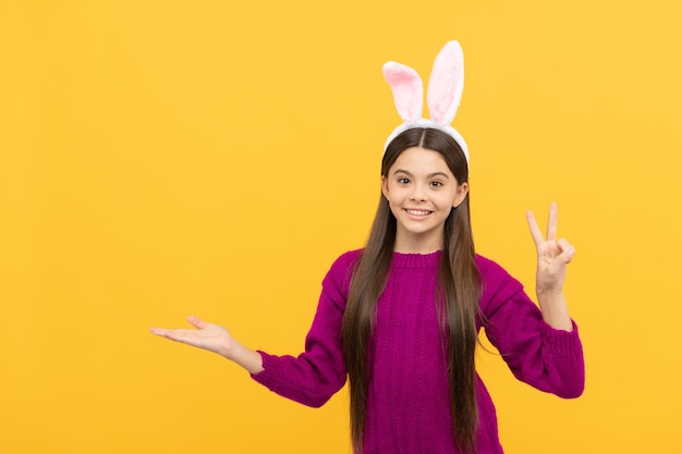 Adorable niño con divertidas orejas de liebre pascua primavera vacaciones copia espacio feliz adolescente niña usar orejas de conejo presentando producto feliz pascua infancia felicidad niño disfrazado de conejo tiempo para divertirse