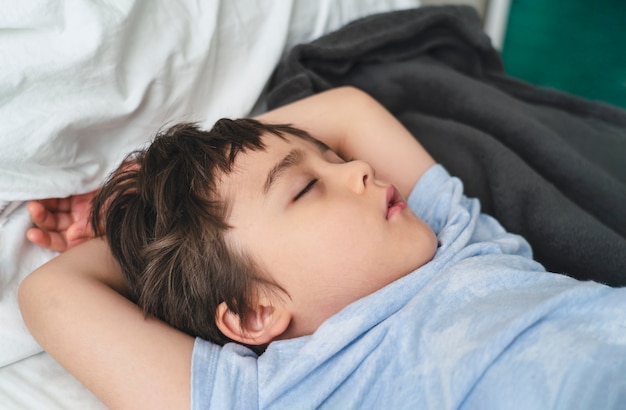 Adorable niño duerme profundamente en la cama por la mañana, niño durmiendo en la cama.