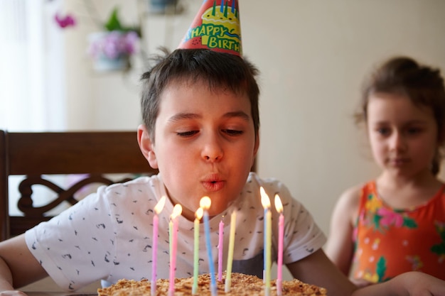 Adorable niño europeo soplando las velas de un pastel de cumpleaños mientras celebra su décimo cumpleaños en casa Concepto de fiesta de cumpleaños