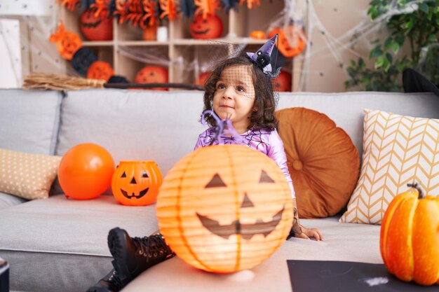 Adorable niño hispano que tiene una fiesta de halloween con un juguete de calabaza en casa