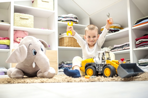 Foto adorable niño jugando con juguetes mientras está sentado en el suelo de su sala de juegos