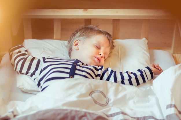 Adorable niño pequeño durmiendo en su cama. Niño soñoliento