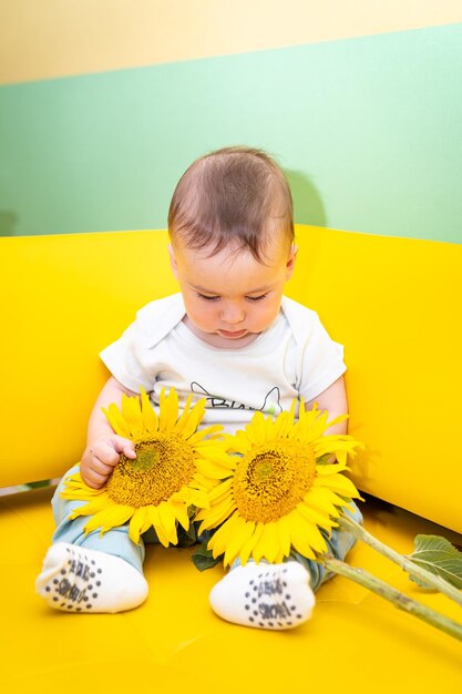 Adorable niño pequeño con flor Pequeño lindo bebé sentado con girasol