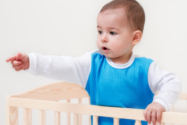 Adorable niño pequeño indica con la mano y el dedo sobre fondo blanco.