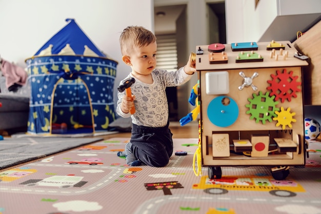 Adorable niño pequeño jugando juegos interactivos para un buen desarrollo en casa.