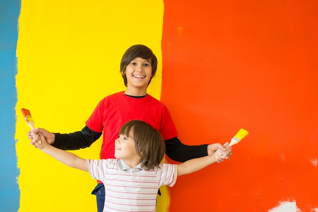 Adorable niño en pintura brillante con lío de pintura niño en la pared