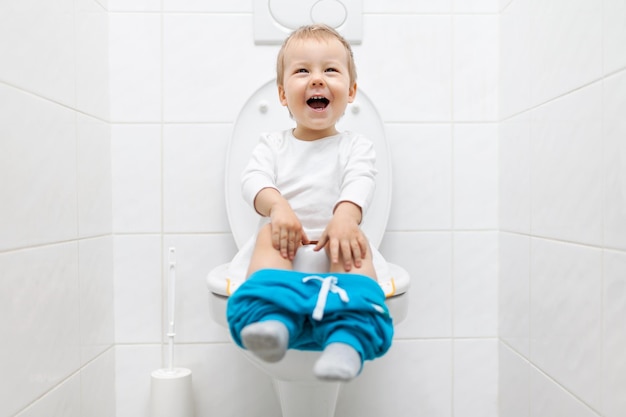 Adorable niño sentado en el inodoro