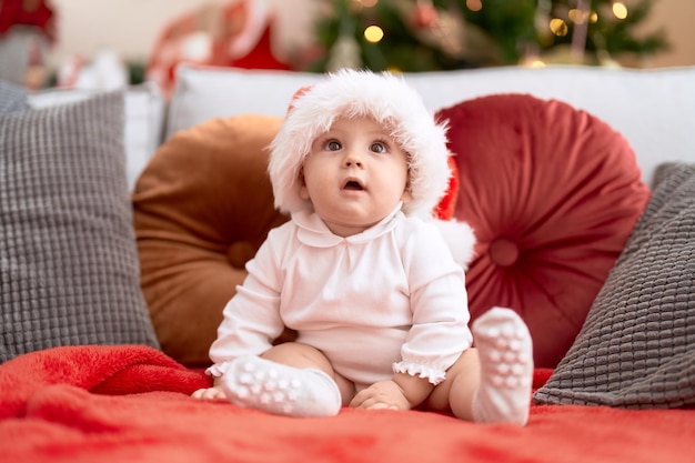 Adorable niño con sombrero de navidad sentado en el sofá en casa