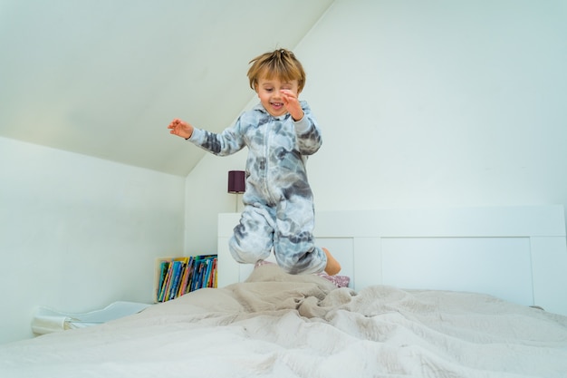 Adorable niño de tres años jugando en el dormitorio en casa