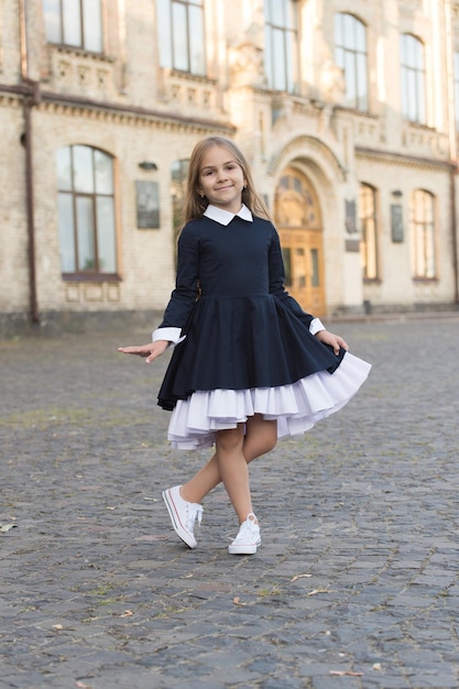 Adorable niño usa un elegante vestido de uniforme con un aspecto elegante en la escuela del patio de la escuela