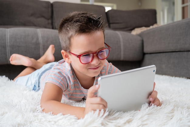 Adorable niño usando una tableta digital en el suelo en casa