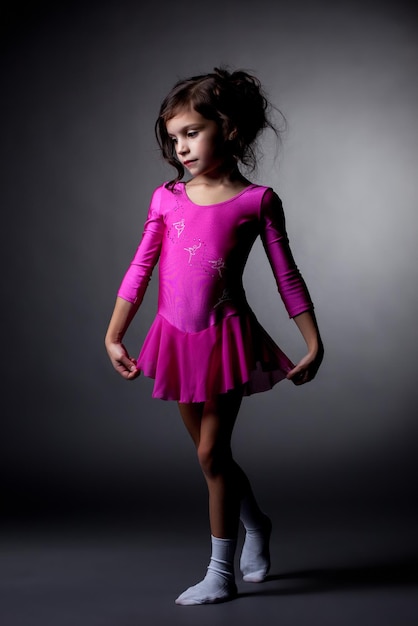 Adorable pequeña gimnasta posando en vestido rosa
