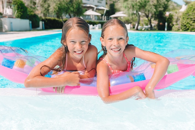 Adorables hermanitas juegan en la piscina al aire libre