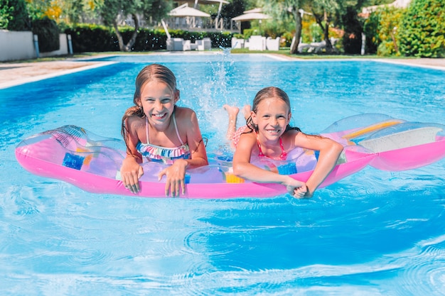 Adorables hermanitas juegan en la piscina al aire libre