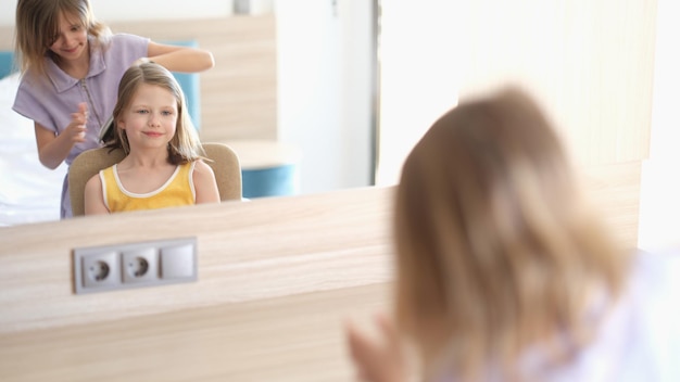 Las adorables hermanitas que usan un peine están sentadas en el interior