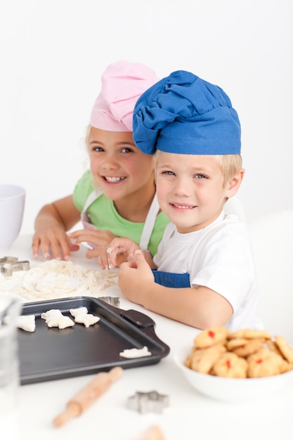 Adorables hermanos amasando juntos una masa en la cocina