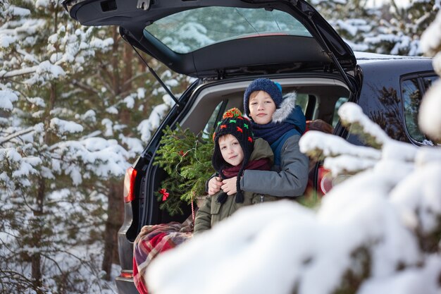 Adorables hermanos sentados en el coche en el bosque nevado de invierno