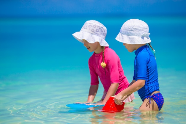 Adorables niñas felices divertirse en aguas poco profundas en vacaciones en la playa