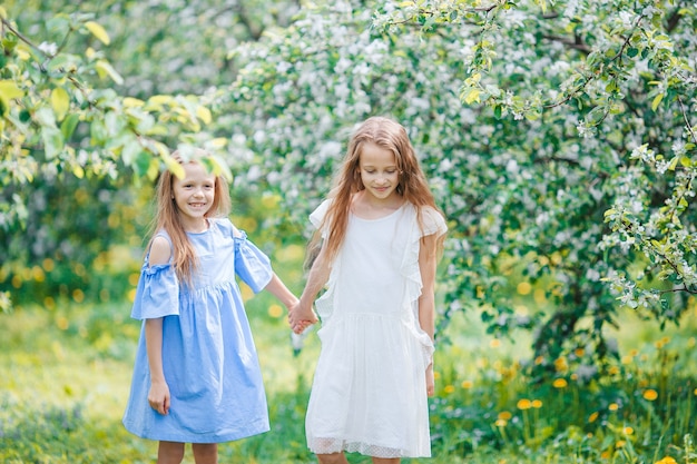 Adorables niñas en el jardín floreciente del manzano en primavera