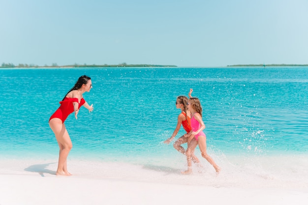 Adorables niñas y joven madre en tropical playa blanca