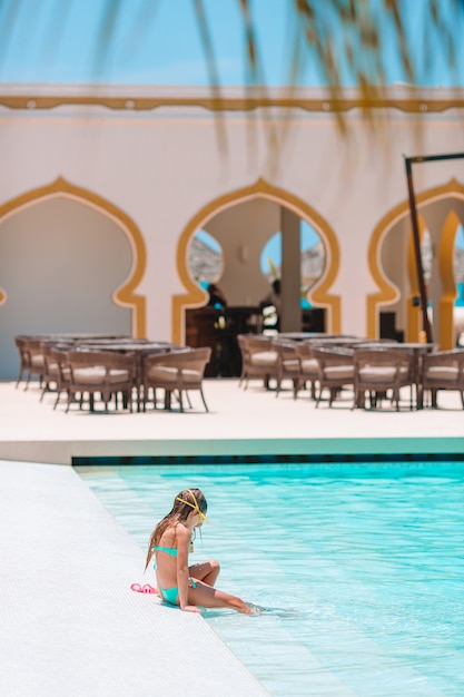 Adorables niñas jugando en la piscina al aire libre de vacaciones