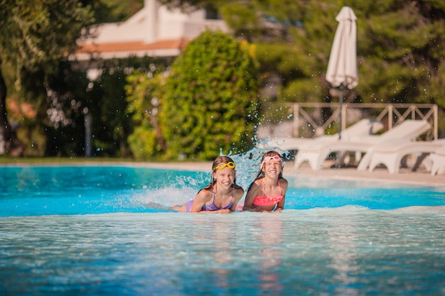 Adorables niñas jugando en la piscina al aire libre