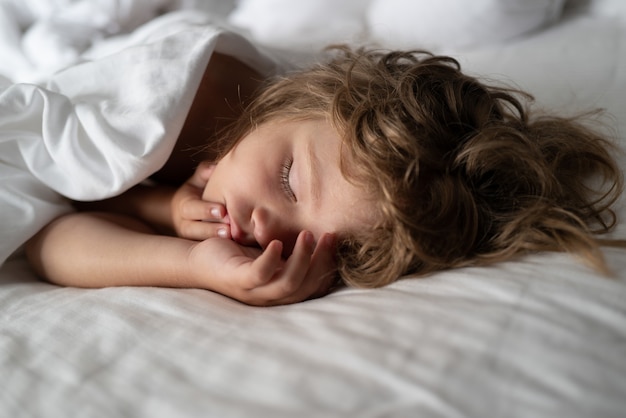 Los adorables niños pequeños descansan dormidos, disfrutan de un buen sueño saludable y pacífico o de una siesta. Niño de seis años durmiendo en la cama.