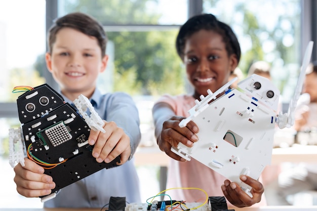 Adorables niños preadolescentes inspeccionando el taller de vehículos robóticos