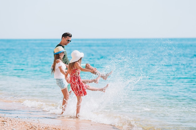 Adorables niños y su padre en la playa durante las vacaciones de verano