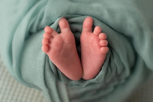 Foto adorables pies de bebé cubiertos con una manta verde concepto de maternidad y niñez