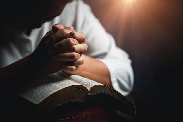 Adoração cristã com conceito de bíblia Mão de pessoa jovem segurando a bíblia sagrada com estudo em casa Cristão feminino adulto lendo livro na igreja Menina aprendendo religião espiritualidade e orando a deus