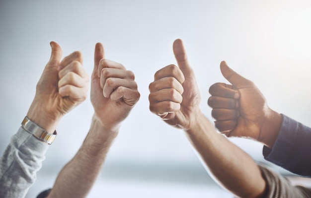 Adoramos o que você está fazendo Captura de um grupo de empresários irreconhecíveis mostrando polegares para cima em um escritório