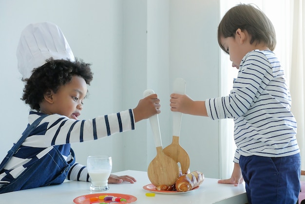 Adoráveis crianças brincando com uma cozinha de brinquedo usando chapéu de chef. Brinquedos educativos para crianças.