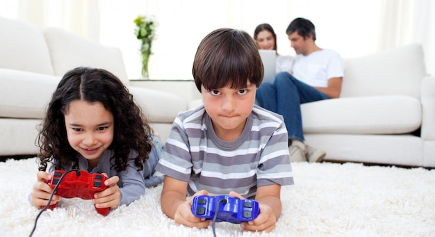 Adoráveis ​​irmãos jogando videogame no chão