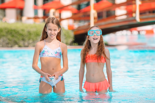 Adoráveis meninas brincando na piscina de férias