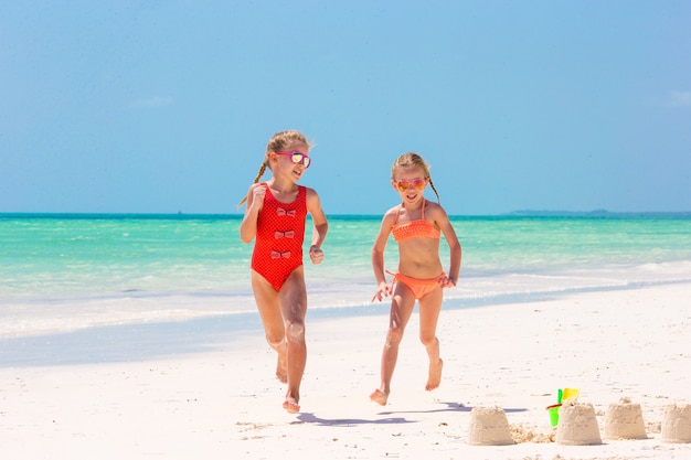 Adoráveis meninas durante as férias de verão. Crianças brincando com brinquedos de praia na praia branca